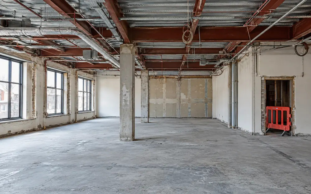 Vacant commercial interior with exposed ceiling beams and service routes